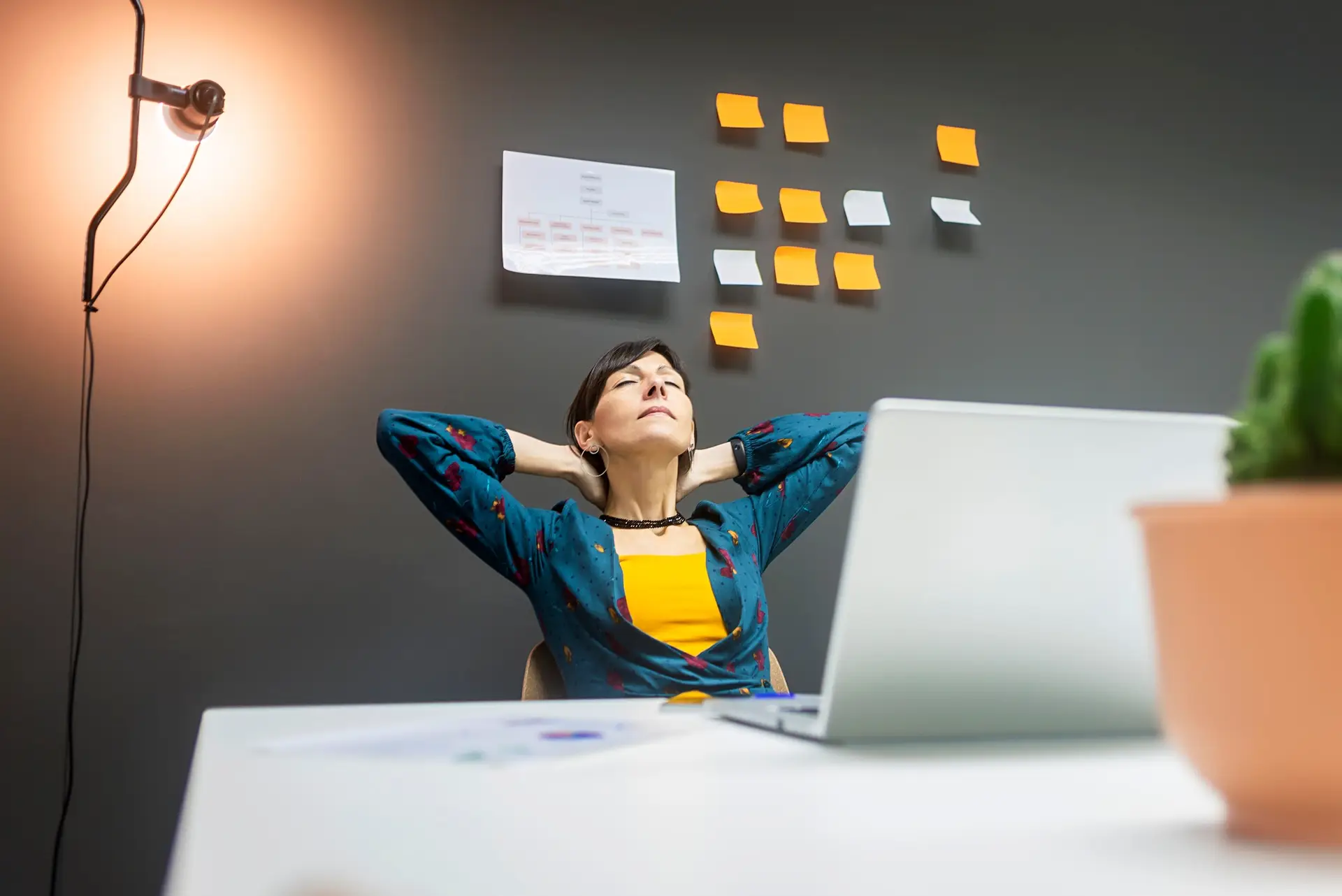 Smiling businesswoman stretching while working with laptop