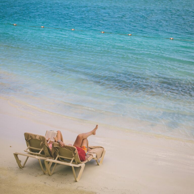 Two vacationers relaxing by a turquoise ocean on a double chaise lounge in Jamaica