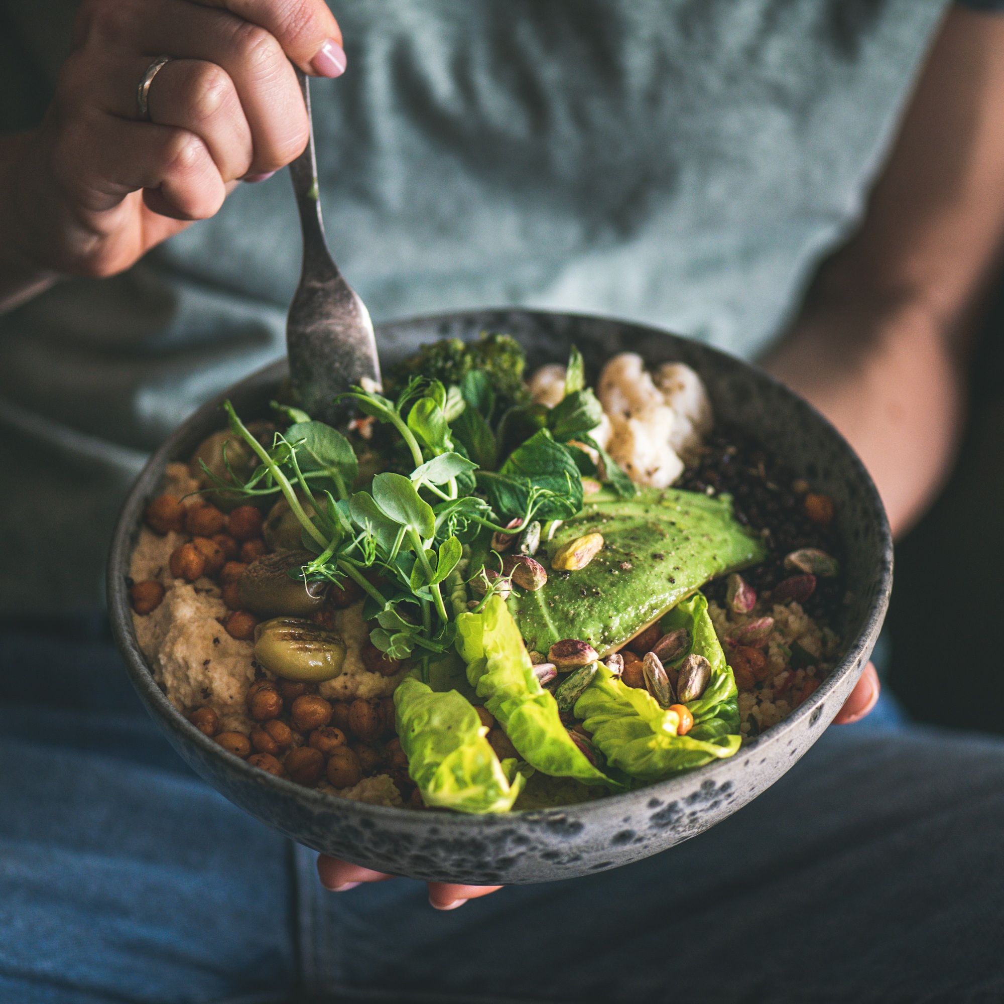 Woman eating healthy vegan dish from bowl, square crop